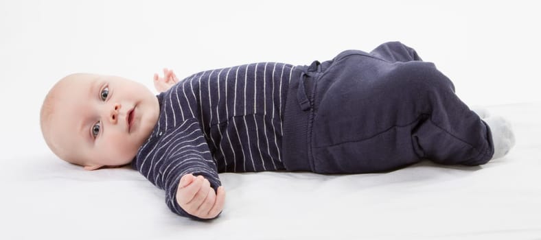 smiling toddler in blue clothing laying down. vertical image