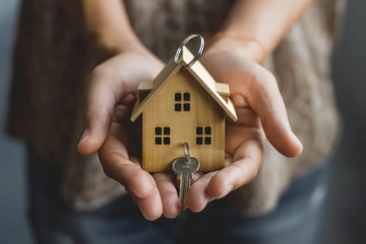 Hands holding a house model and keys, real estate investment concept