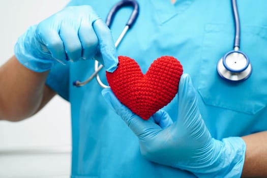 Asian woman doctor holding red heart for health in hospital.