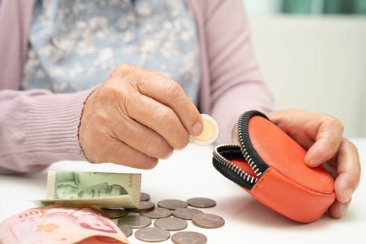 Asian senior or elderly old lady woman holding counting coin money in bag. Poverty, saving problem in retirement.