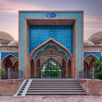 The stunning Imamzadeh Mausoleum in Ganja, Azerbaijan features intricate tile designs. The scene captures the beauty of the structure under a colorful sunset, highlighting its architectural details