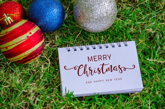 Top view of Merry Christmas and Happy New Year text on notepad with Christmas decoration background. Christmas Season Celebration.