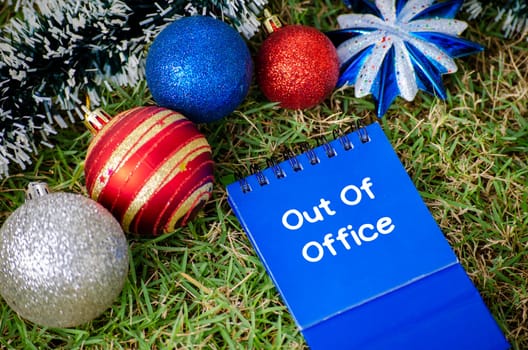 Top view of Out Of Office text on blue notepad with Christmas decoration background. Christmas Season and Happy Holiday concept.