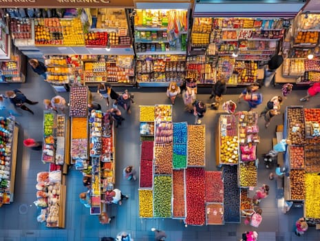 A bustling market with colorful stalls and people, viewed from above, showcasing a lively atmosphere.