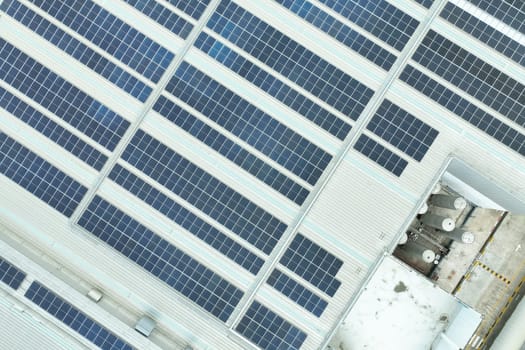 Solar energy for factory and warehouse building. Solar panels on roof of industrial plant. Commercial solar power. Rooftop solar power. Rooftop renewable energy system. Sustainable green energy.