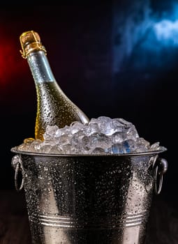 Bottle of sparkiling wine in bucket with crushed ice.