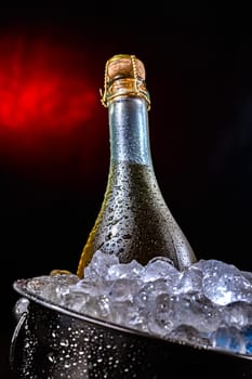 Bottle of sparkiling wine in bucket with crushed ice.