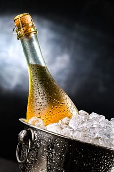 Bottle of sparkiling wine in bucket with crushed ice.
