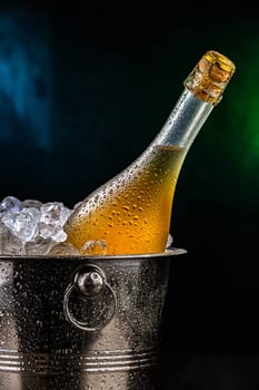 Bottle of sparkiling wine in bucket with crushed ice.