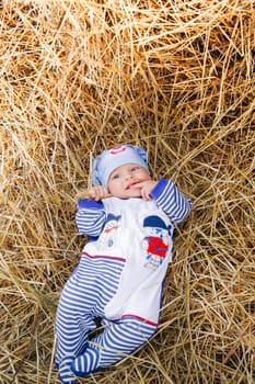 A cute little baby peacefully lying in a bed of straw, wearing a charming outfit along with a lovely hat