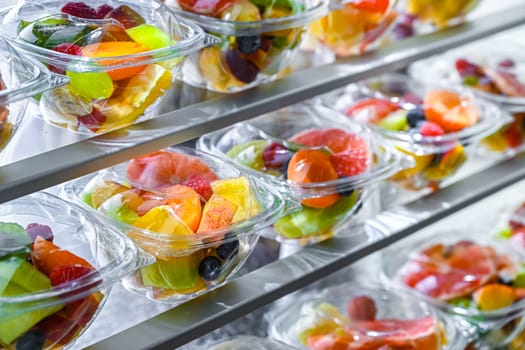 Plastic boxes with pre-packaged fruit salads, put up for sale in a commercial refrigerator
