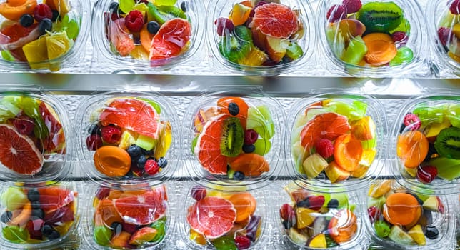 Plastic boxes with pre-packaged fruit salads, put up for sale in a commercial refrigerator