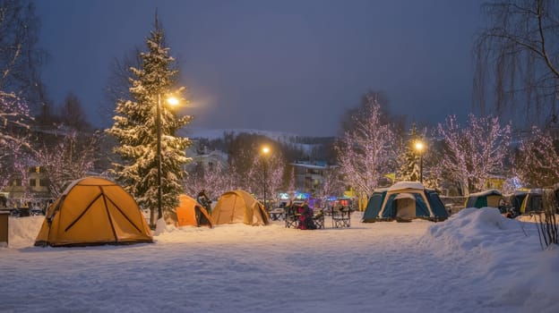 Colorful tents are set up in a snowy area lit by festive lights during twilight creating a magical winter atmosphere for campers.