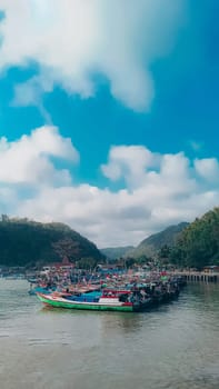A large group of boats are floating on a lake. The sky is blue with some clouds