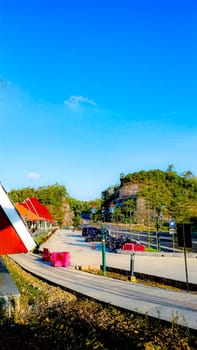 A peaceful roadside view featuring a red-roofed building, clear blue sky, and greenery along a mountain road, creating a tranquil atmosphere.