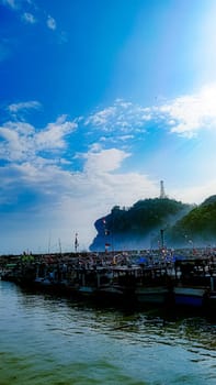 A large group of boats are floating on a lake. The sky is blue with some clouds