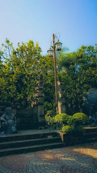 Serene garden featuring stone sculptures and lush greenery under a clear blue sky. Tranquil setting with historic elements and natural beauty, ideal for relaxation and contemplation.