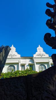 A stunning colonial building with intricate architectural details. Vibrant greenery adds charm against a clear blue sky. Perfect for concepts of history, architecture, and nature in harmony.