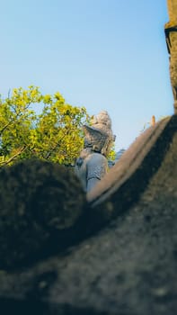Serene garden featuring stone sculptures and lush greenery under a clear blue sky. Tranquil setting with historic elements and natural beauty, ideal for relaxation and contemplation.