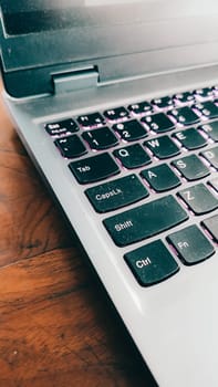 Grey and black laptop. A user placing laptop computer on desk in home office. Close up view.