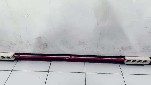 A red and white striped object is on the floor. The red stripe is on the bottom of the object