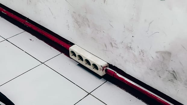 A red and white striped object is on the floor. The red stripe is on the bottom of the object