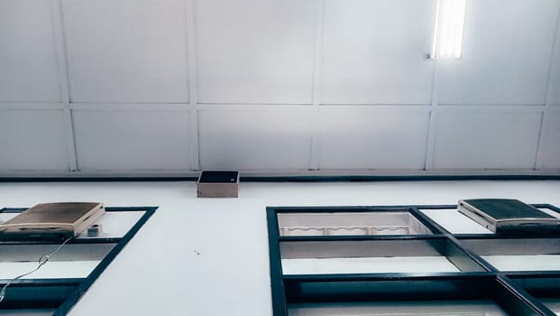 A low-angle view of a modern ceiling featuring two air conditioning units and fluorescent lighting, depicted in a minimal and clean design style.