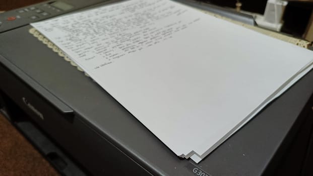 Close-up of a stack of printed papers resting on an office printer tray, highlighting everyday office tasks and technology. Suitable for illustrations about printing, office work, and document management.