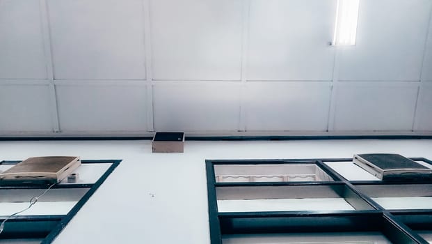 A low-angle view of a modern ceiling featuring two air conditioning units and fluorescent lighting, depicted in a minimal and clean design style.