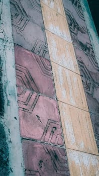 A vibrant geometric pattern of sidewalk tiles in contrasting colors of red and yellow. The detailed texture and design enhance urban aesthetics and architectural interest.