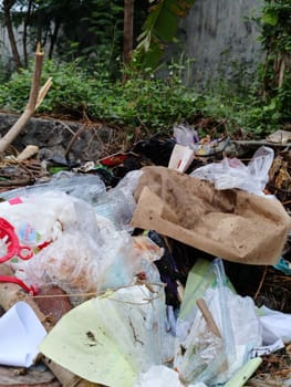 Image showcasing discarded waste, including plastics and paper, in a natural setting. Highlights the environmental impact and challenges of pollution. Emphasizes the need for proper waste management.