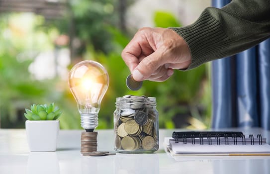 Hand with money coins in clear glass, Business investment growth concept, saving concept, Hand putting coin in clear jar.
