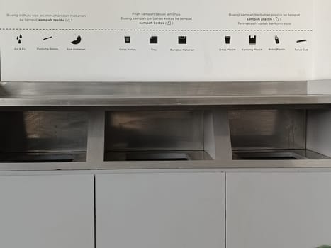 A photo featuring modern waste segregation bins, clearly labeled with instructional signs for efficient waste disposal. Promotes recycling and environmental awareness in a public space.