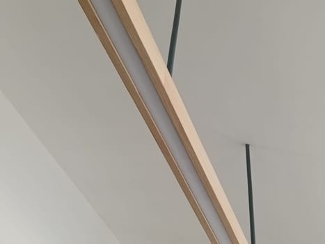 A close-up image of a modern minimalist ceiling light fixture with sleek lines and wooden accents, perfect for contemporary interior decor.