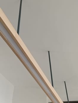 A close-up image of a modern minimalist ceiling light fixture with sleek lines and wooden accents, perfect for contemporary interior decor.