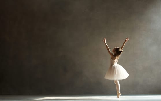 A young ballerina gracefully performs in a studio, demonstrating elegance and poise with ample copy space.