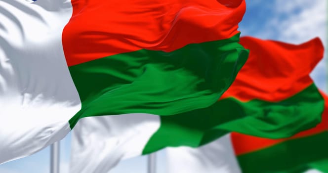 National flag of Madagascar waving in the wind on a clear day. Two horizontal bands of red and green, with a white vertical band on the left. 3d illustration render. Rippling fabric. Selective focus