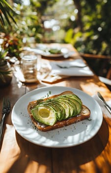 A delicious plate of avocado toast garnished with lemon slices and herbs is showcased on a sunny, outdoor dining table surrounded by greenery.