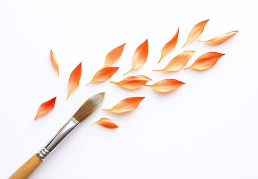 An arrangement of orange petal shapes and a paintbrush on a white background highlights a creative design process in art.