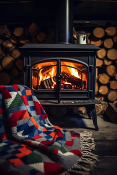 A warm, inviting atmosphere is created by a wood stove with flames, complemented by a vibrant blanket and a stocked woodpile nearby.