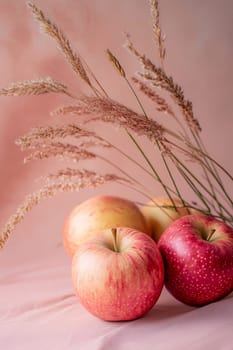 Freshly picked red and yellow apples arranged artistically with dried grass, creating a warm, inviting atmosphere.