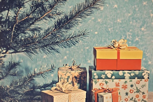 Colorfully wrapped holiday presents are arranged beneath a Christmas tree against a charming snowflake-patterned background.