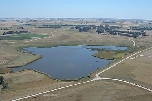 Aerial view of a blue lake surrounded by farmland and prairie, showcasing rural landscape diversity