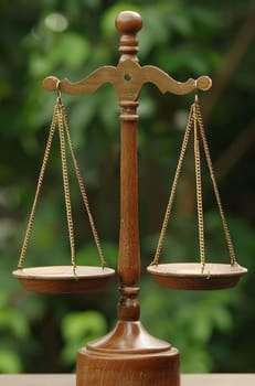 Decorative golden balance scales against lush green background, symbolizing environmental law