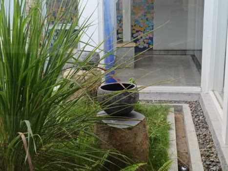 A serene indoor garden with lush greenery and a decorative stone pot. The setup provides a calming aesthetic, perfect for relaxation and contemplation.