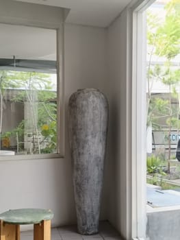 A tall decorative vase adds an artistic touch to a minimalist modern interior. Surrounded by natural light and greenery, this scene exudes tranquility and elegance in contemporary design.