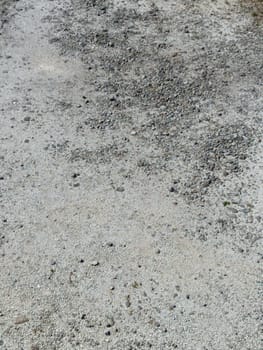 Close-up view of a gravel surface featuring scattered rocks and pebbles displaying an earthy texture under sunlight. Ideal for backgrounds and design projects.