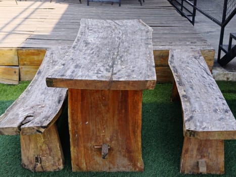 A rustic wooden table and benches set on an outdoor patio, showcasing natural, handcrafted design. Ideal for gatherings, creating a cozy and organic atmosphere.