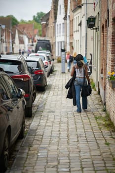 Footpath in the old town of Bruges in Belgium with a young woman of African descent