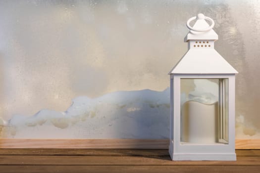 lantern with candle wooden board near heap snow through window. High resolution photo